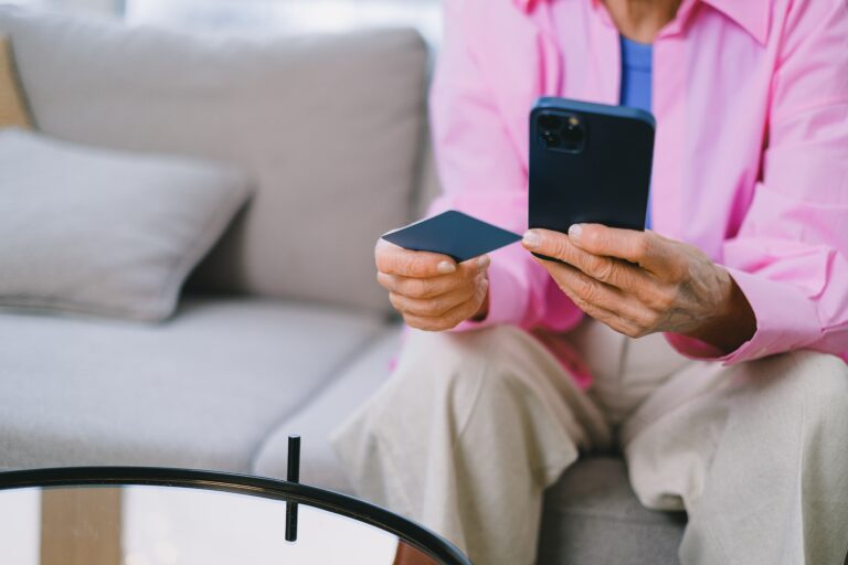 mulher sentada, segura um celular e um cartão