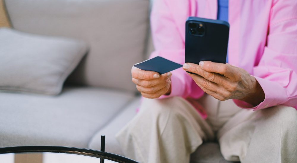 mulher sentada, segura um celular e um cartão